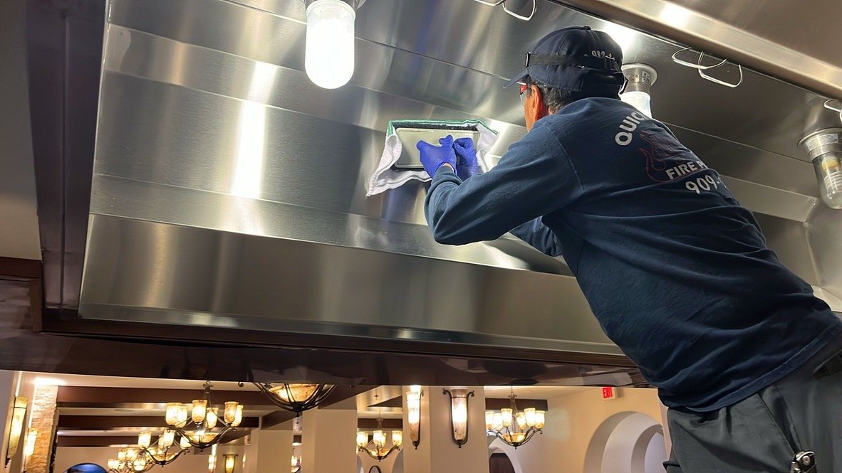 Technicians cleaning a commercial kitchen hood and exhaust system to reduce fire hazards