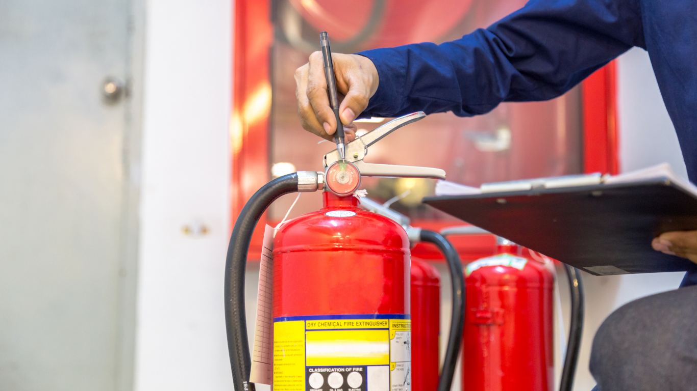 Technician installing and inspecting fire extinguishers in a commercial property - Quick Response Fire Protection